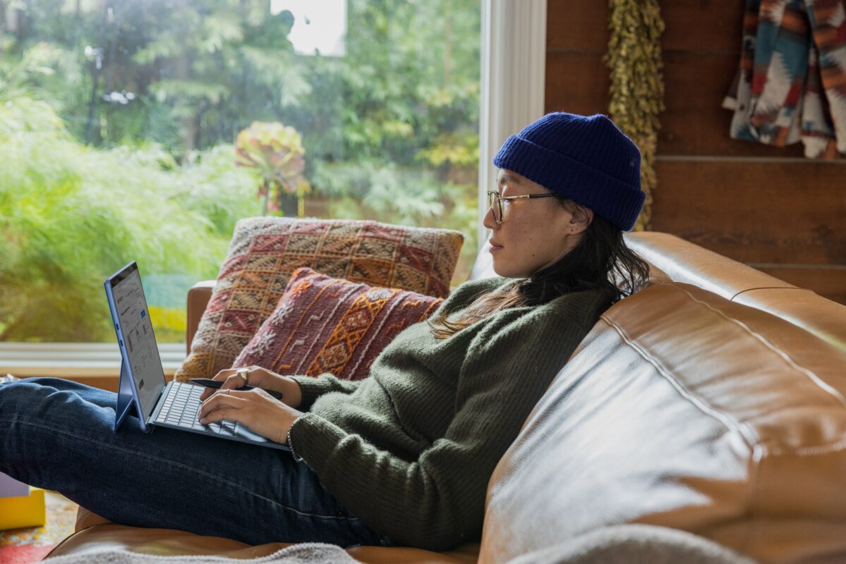 Asian woman working on computer sitting on couch